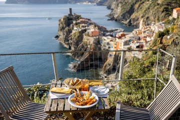 Fototapeten Served lunch table with seafood on coast at Vernazza village in Italy. Concept of mediterranean seafood and summer vacations © rh2010