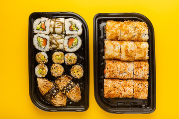 Delicious sushi rolls in disposable boxes on a yellow background. Food delivery concept. Food in the office. Japanese food. Flat lay top view, with copy space and space for text.