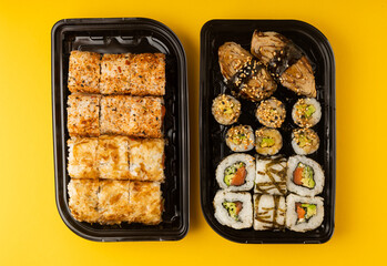 Delicious sushi rolls in disposable boxes on a yellow background. Food delivery concept. Food in the office. Japanese food. Flat lay top view, with copy space and space for text.