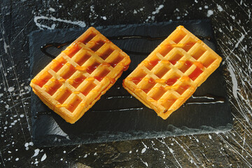 Sweet waffles poured with honey on a slate board.
