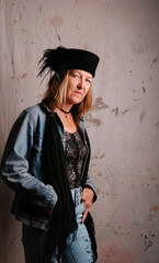 portrait of woman in feathered hat and jean outfit with unsure expression