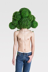 topless young guy in jeans stands in a mask in the form of a huge broccoli
