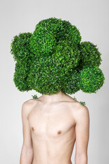 portrait of the topless young guy in a mask in the form of a huge broccoli