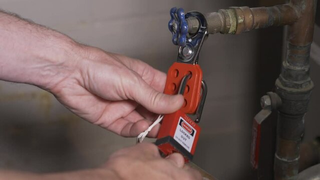 A close up view of a worker removing a lock-out tag-out lock from a machine.  	