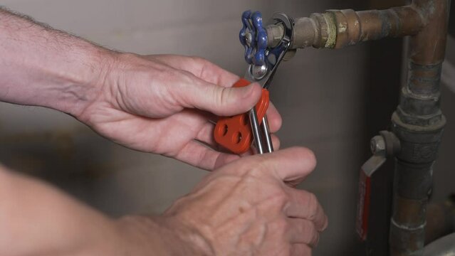 A close up view of a worker attaching a lock-out tag-out lock on a machine.  	
