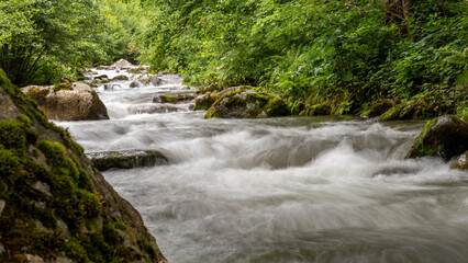 Dripping river in the mountains, its rocks and lush vegetation