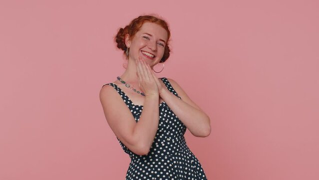 Happy redhead woman in polkadot dress shouting, raising fists in gesture I did it, celebrating success, winning, birthday, lottery goal achievemen. Young girl indoor on pink studio wall background
