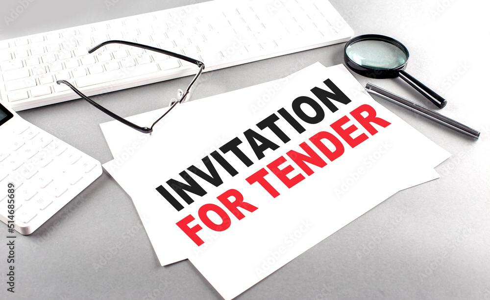 Aufkleber invitation for tender text on a paper on a gray background near a calculator and a white keyboard