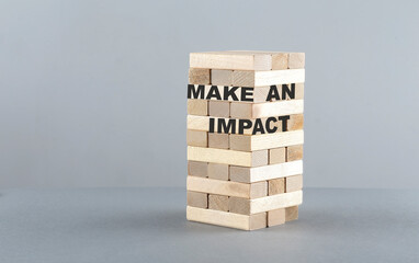 MAKE AN IMPACT text on wooden block , grey background