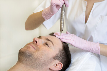 Doctor female dermatologist trichologist makes a procedure to stimulate hair growth to a patient man. Laser treatment of alopecia and hair loss .Close up