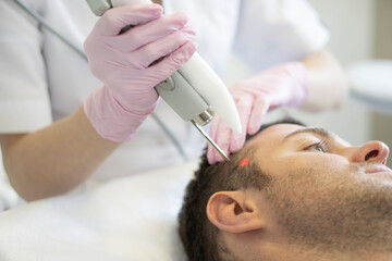 Doctor female dermatologist trichologist makes a procedure to stimulate hair growth to a patient...