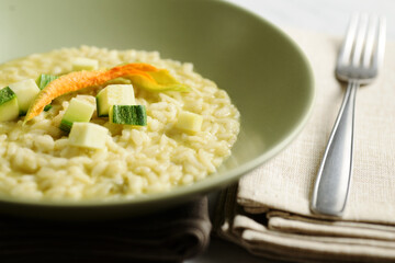 risotto dish with zucchini and a fork on a beige napkin
