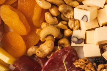 close up of charcuterie board with different types of nuts, salami, apricot and cheese