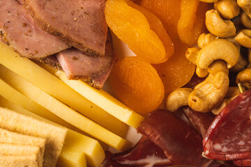 close up of charcuterie board with different types of nuts, pastrami, salami, apricot and cheese