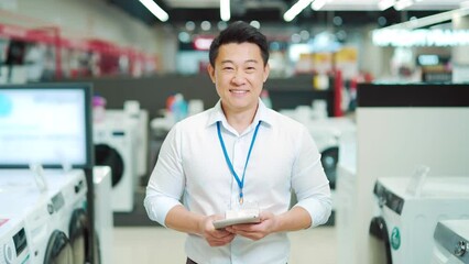 portrait smiling male asian sales consultant Expert who is standing in a home appliance store looking at camera. Employee Man worker seller smiles. salesman vendor with a tablet in his hands