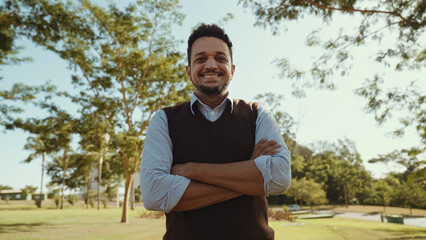 Portrait of young man with crossing hands in the casual shirt in the farm on the colorful sky background.