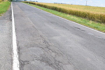 sehr beschädigte Straße mit Schlaglöchern und WEllen