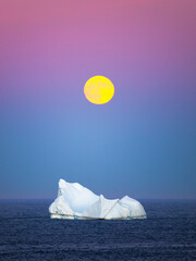 Pastel colored moonrise over an iceberg