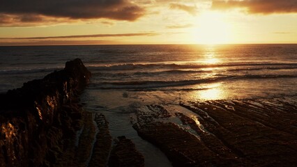 Beautiful rocky shore  with sun during sunset.  Drone view over waves of the ocean during sunset.  Aerial View of rolling waves with skyline. Relax and meditation.  Oceanscape  in Portugal