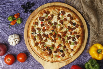 Flatbread pizza garnished with fresh angular on wooden pizza board top view dark stone background