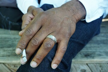 Schöne schlanke Hand von afrikanischem Mann mit silbernem Ring liegt auf Jeanshosenbein