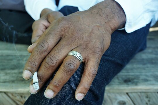 Sch&ouml;ne schlanke Hand von afrikanischem Mann mit silbernem Ring liegt auf Jeanshosenbein