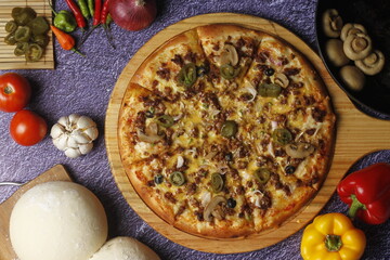Flatbread pizza garnished with fresh angular on wooden pizza board top view dark stone background