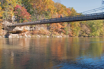 A hiker crosses a suspension bridge over Sugar Creek in Turkey Run State Park, Indiana.