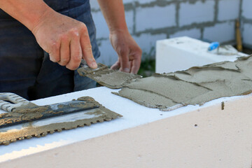 The bricklayer applies the adhesive before stealing the bricks or building blocks. The concept of...