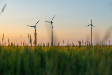 View of wind power turbines, part of a wind farm. Wind turbines on green field in countryside. Wind power plant.