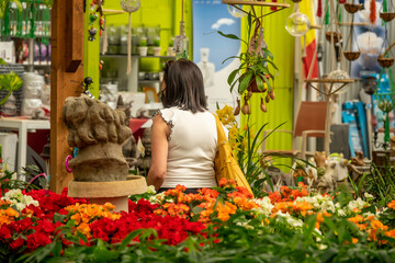 Woman seen from behind looking at plants and flowers inside a flower shop