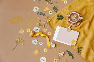 Spring desktop mockup scene, yellow flowers with coffee cup and Blank greeting card mockup. Easter concept, Flat lay, top view.
