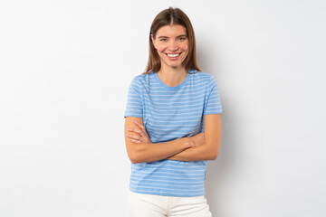Obraz premium Cheerful female of 20s standing against white background with folded arms in striped clothes