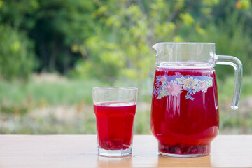 Fototapeta na wymiar Red compote of berries in a glass and jug