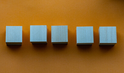 Five wooden cubes on orange background, mocap