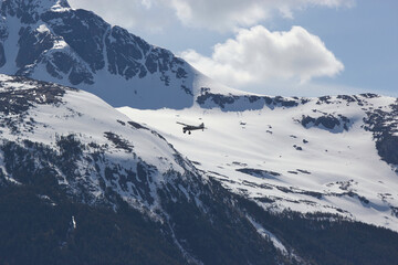 Fototapeta na wymiar Alaskan Plane flying in front of snow covered Alaskan Mountains