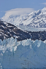 Entire tidewater glacier face with lenticular clouds in the mountains