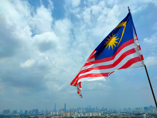 KUALA LUMPUR, MALAYSIA -JULY 1, 2022: The Malaysian flag aka Jalur Gemilang is flown at a high place and against the backdrop of the Kuala Lumpur skyline