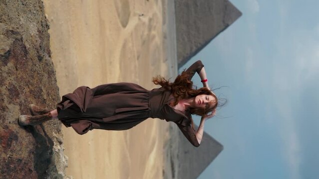 Vertical Instagram video. Young redhead girl in brown dress walking near piramids in Egypt, Cairo - Giza. Copy space