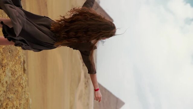 Vertical Instagram video. Young redhead girl in brown dress walking near piramids in Egypt, Cairo - Giza. Copy space