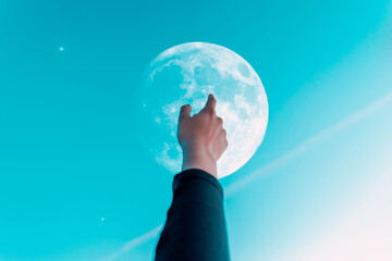 hand of a woman raised to the sky touching or pointing to the moon