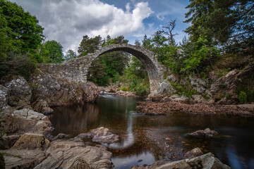 Fototapeta na wymiar The old packhorse bridge across the River Dulnain at Carrbridge was built in 1717. One of the most iconic visitor attractions in the Cairngorms.