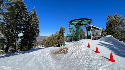 Top of chair lift with orange cones to mark exit path for skiers and snowboarders at Big Bear...