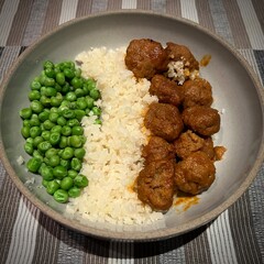 Homemade meatballs, cauliflower rice and peas in a grey ceramic dish on table