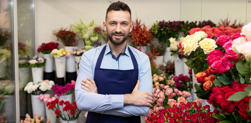 the seller of a fresh flower shop stands in front of a refrigerator with bouquets