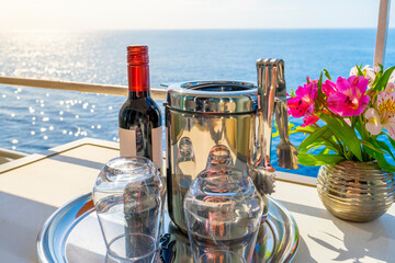 A bottle of red wine, an ice bucket and two stemless glasses next to a bouquet of flowers on the...