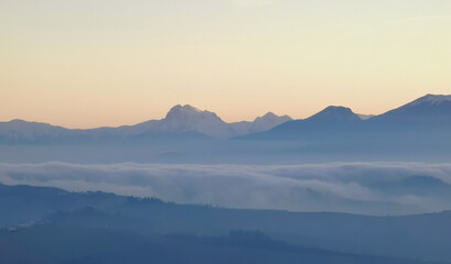 Fototapeta na wymiar Un mare di nebbia e nuvole al tramonto riempie le valli ai piedii dei monti appennini
