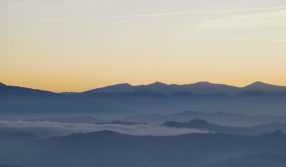 Fototapeta na wymiar Un mare di nebbia e nuvole al tramonto riempie le valli ai piedii dei monti appennini