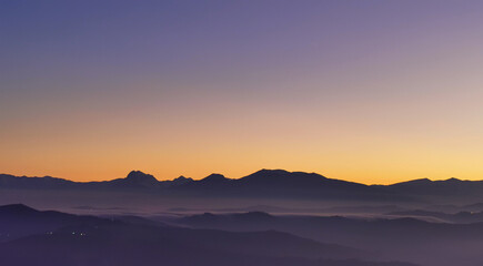 Fototapeta na wymiar Tramonto viola e arancio sui monti le valli e le colline