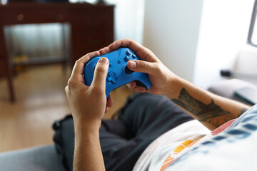 Obraz na płótnie Canvas hands holding and playing with a blue video game controller, details of joystick and buttons, gamer having fun, technology